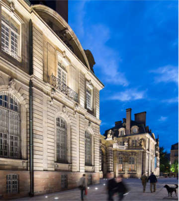 People noticing the architecture lighting in front of a building at Grand Île, Strasbourg lit by Philips lighting