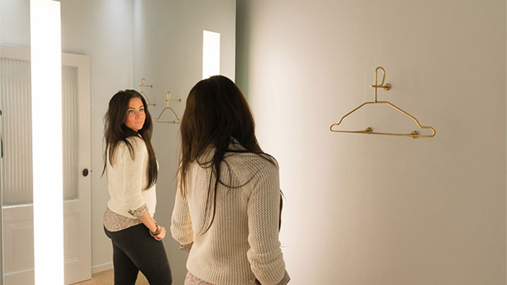 إحدى زبائن متجر سوبر تراش تتفقد مظهرها في مرآة AmbiScene من Philips، باستخدام إعداد ضوء ‘النهار’
