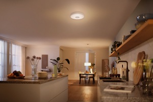 A large kitchen is illuminated with dim light by a ceiling light and a suspended light